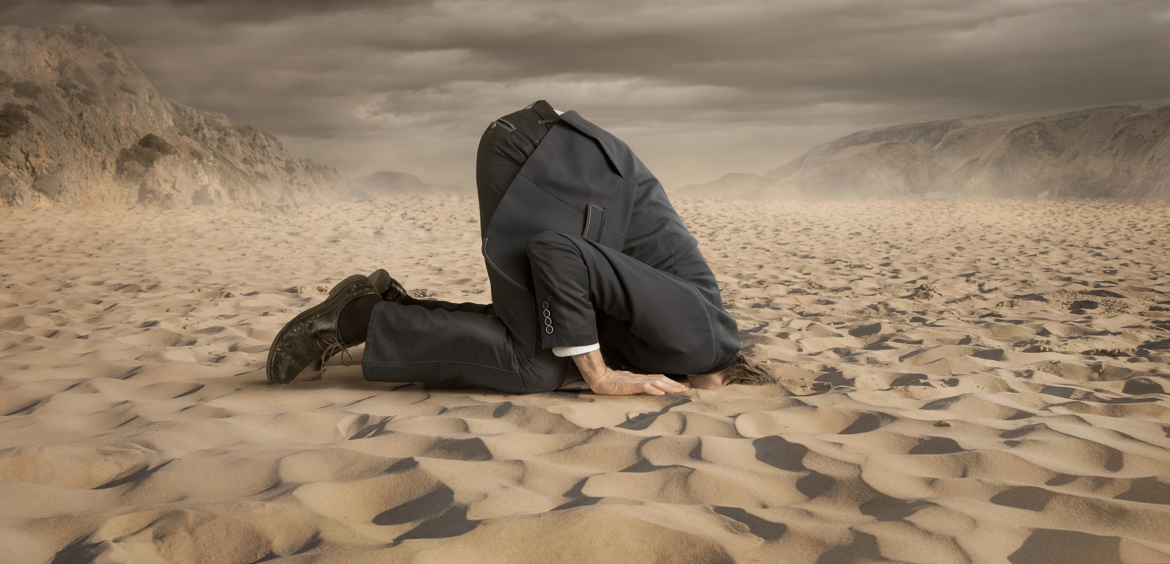 Ein Mann stekct den Kopf in den Sand